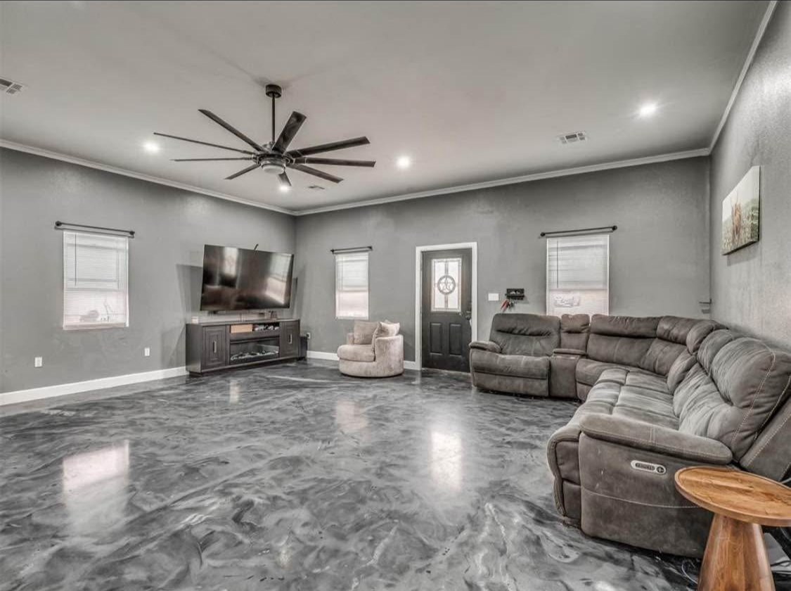 TBC project photo of a living room with sofas, a television, gray walls, polished floor, and a large ceiling fan.