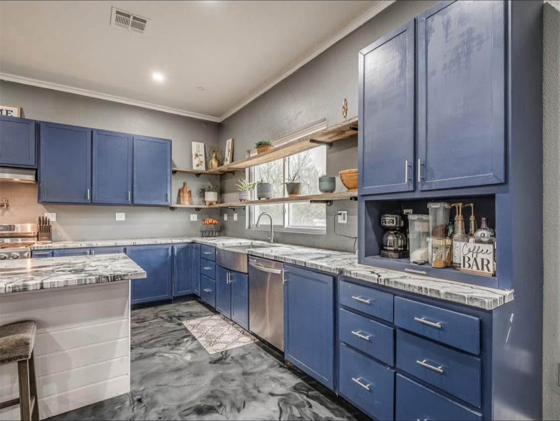TBC project photo of a blue-cabinet kitchen with countertops, open shelves, and a polished patterned floor.