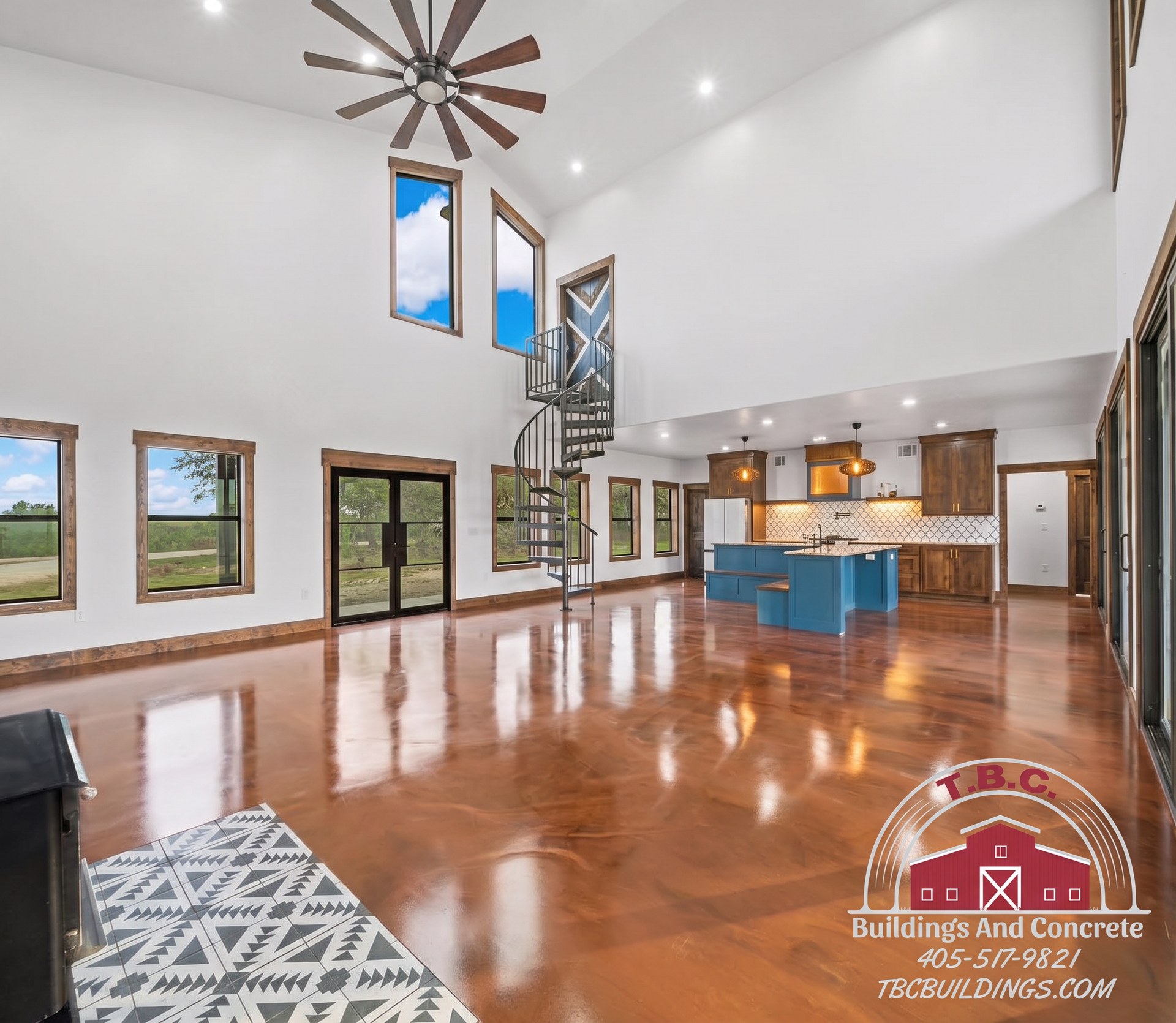 TBC project photo of a finished open living area with tall ceilings, polished floor, and blue kitchen island.