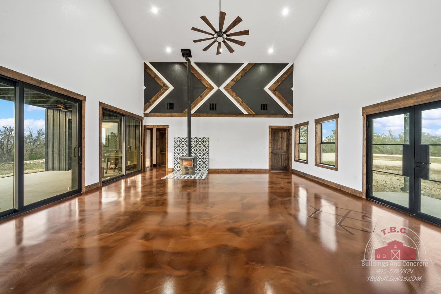 TBC project photo of a finished great room with fireplace, polished floor, and dark ceiling accent.