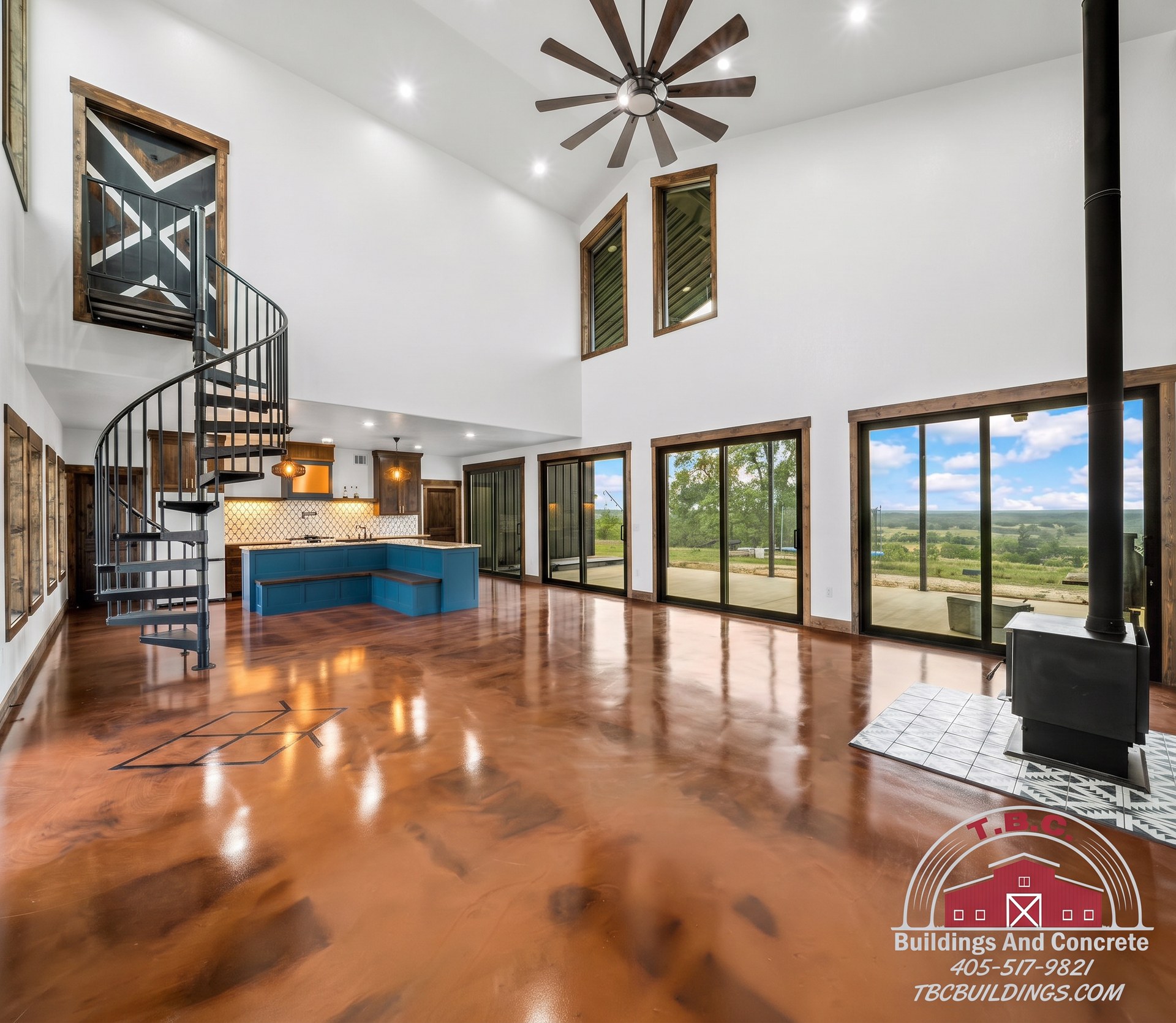 TBC project photo of a finished open great room with blue kitchen island and polished floor.