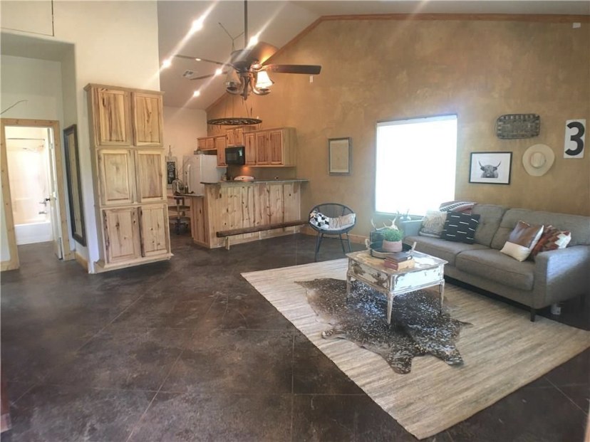TBC project photo of a finished living room and kitchen with wood cabinetry and vaulted ceiling.
