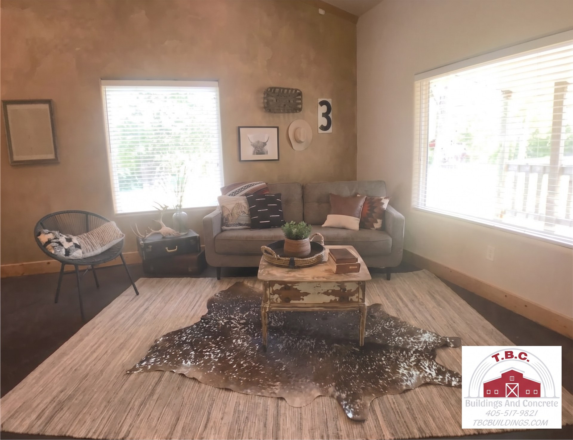 TBC project photo of a finished living room with sofa seating, rug, and large windows.