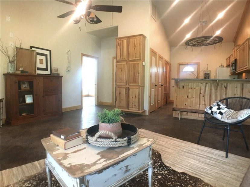 TBC project photo of a finished open living room and kitchen with wood cabinetry and vaulted ceiling.