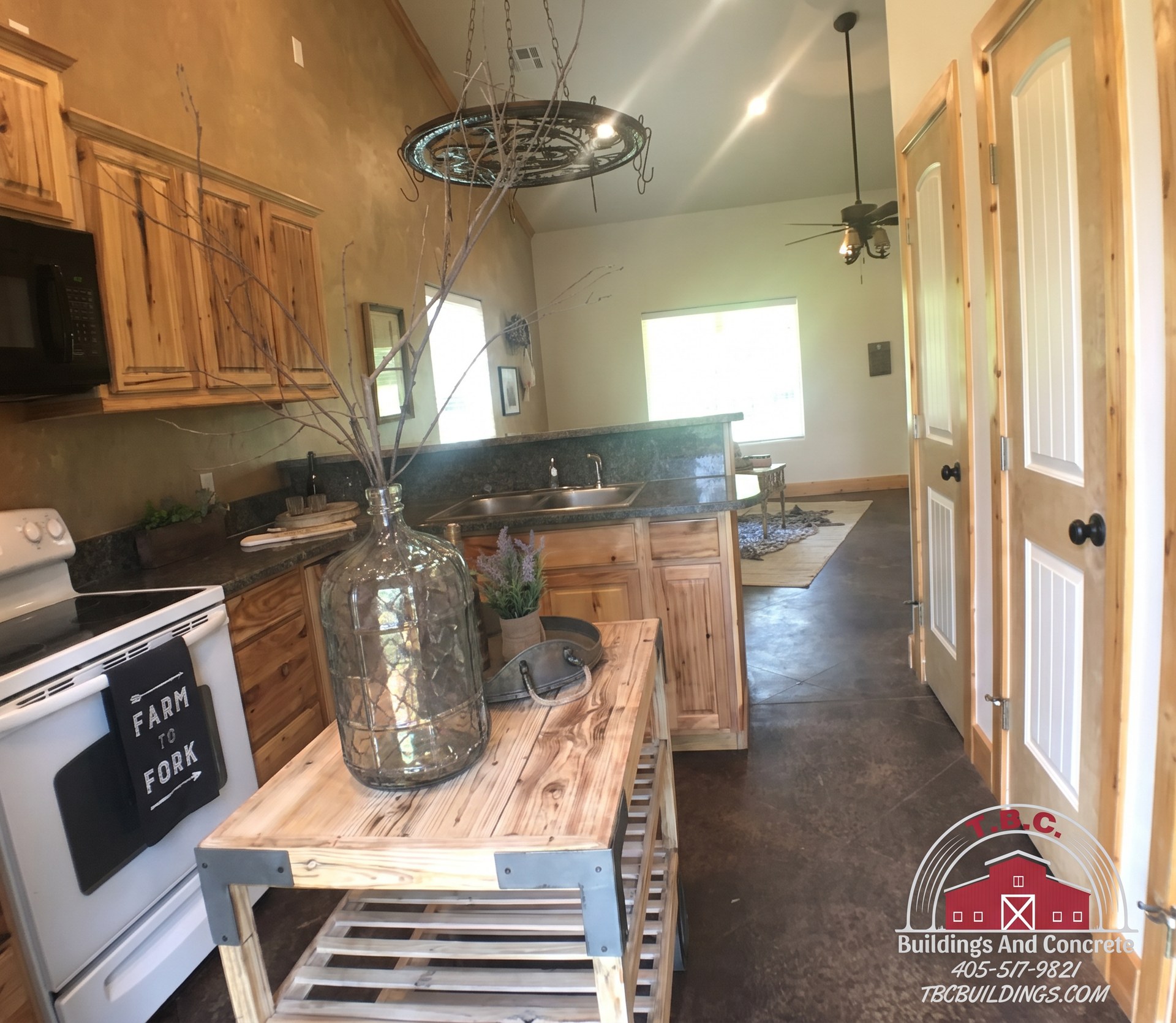 TBC project photo of a finished kitchen with wood cabinetry and dark counters.