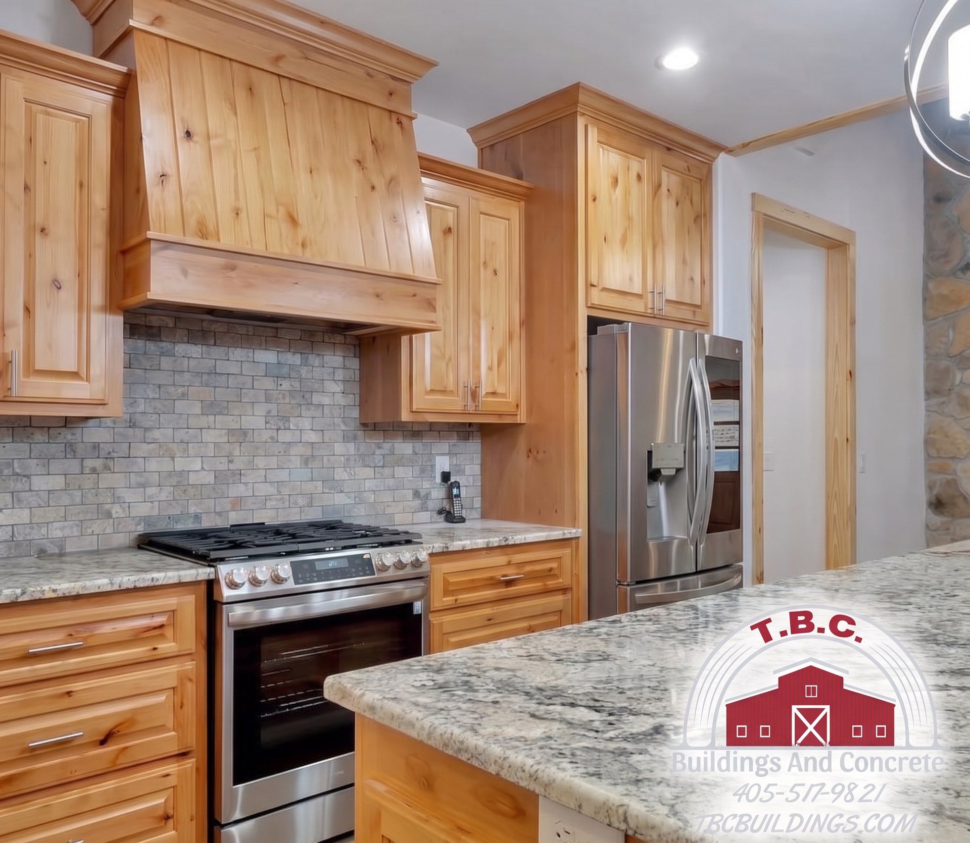 TBC project photo of a kitchen range wall with wood cabinets, gray tile backsplash, granite countertop, and black range.