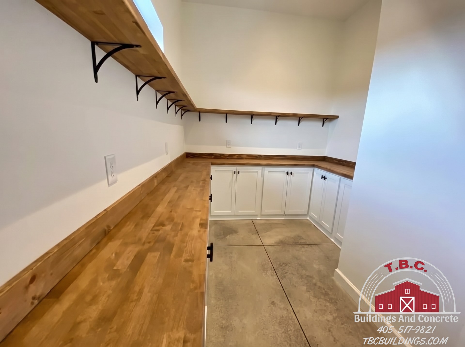 TBC project photo of white kitchen base cabinets with wood countertops, open shelving, and pendant lights.