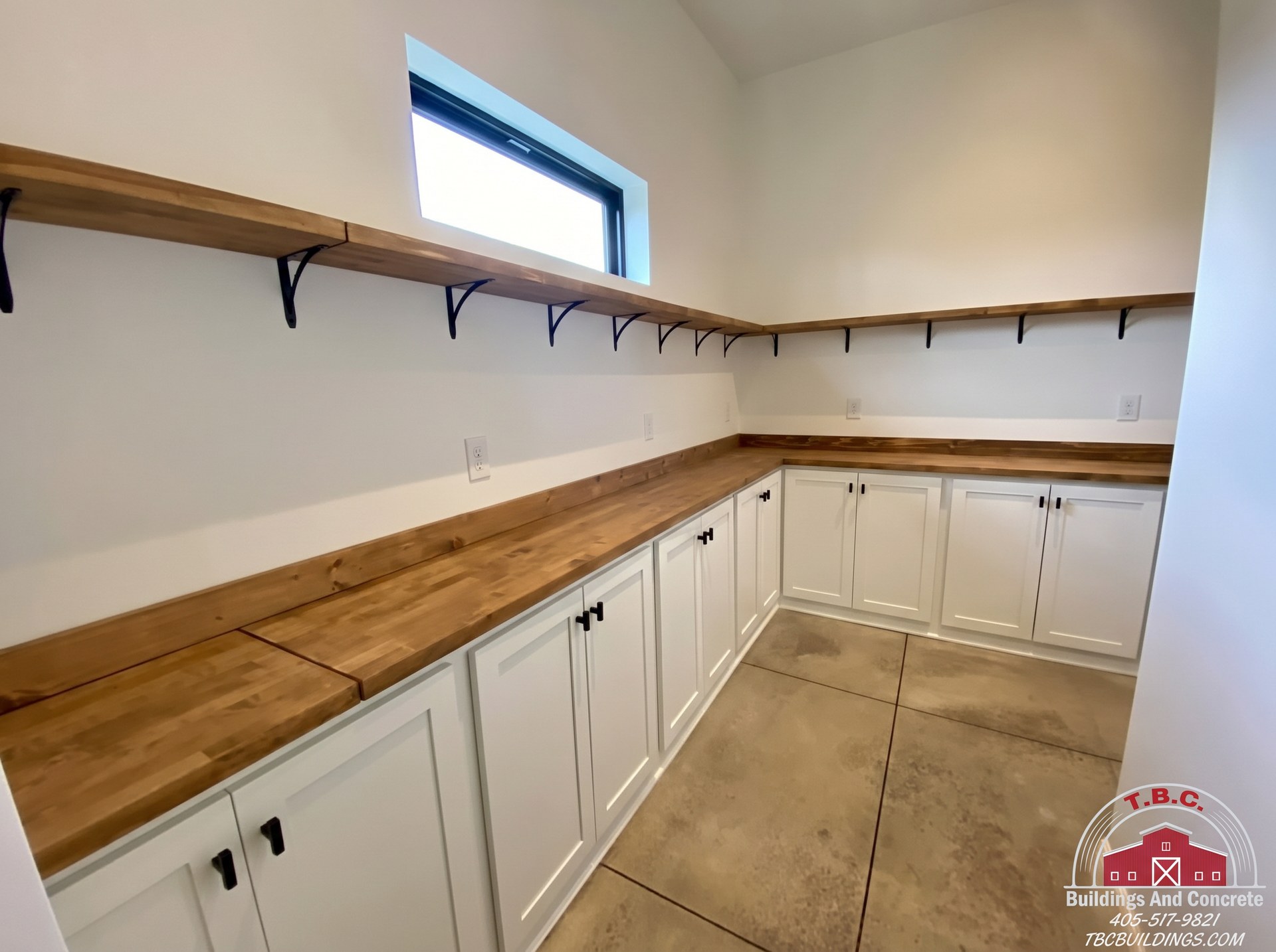 TBC project photo of an L-shaped kitchen with white cabinets, wood countertops, a window, and open shelving.