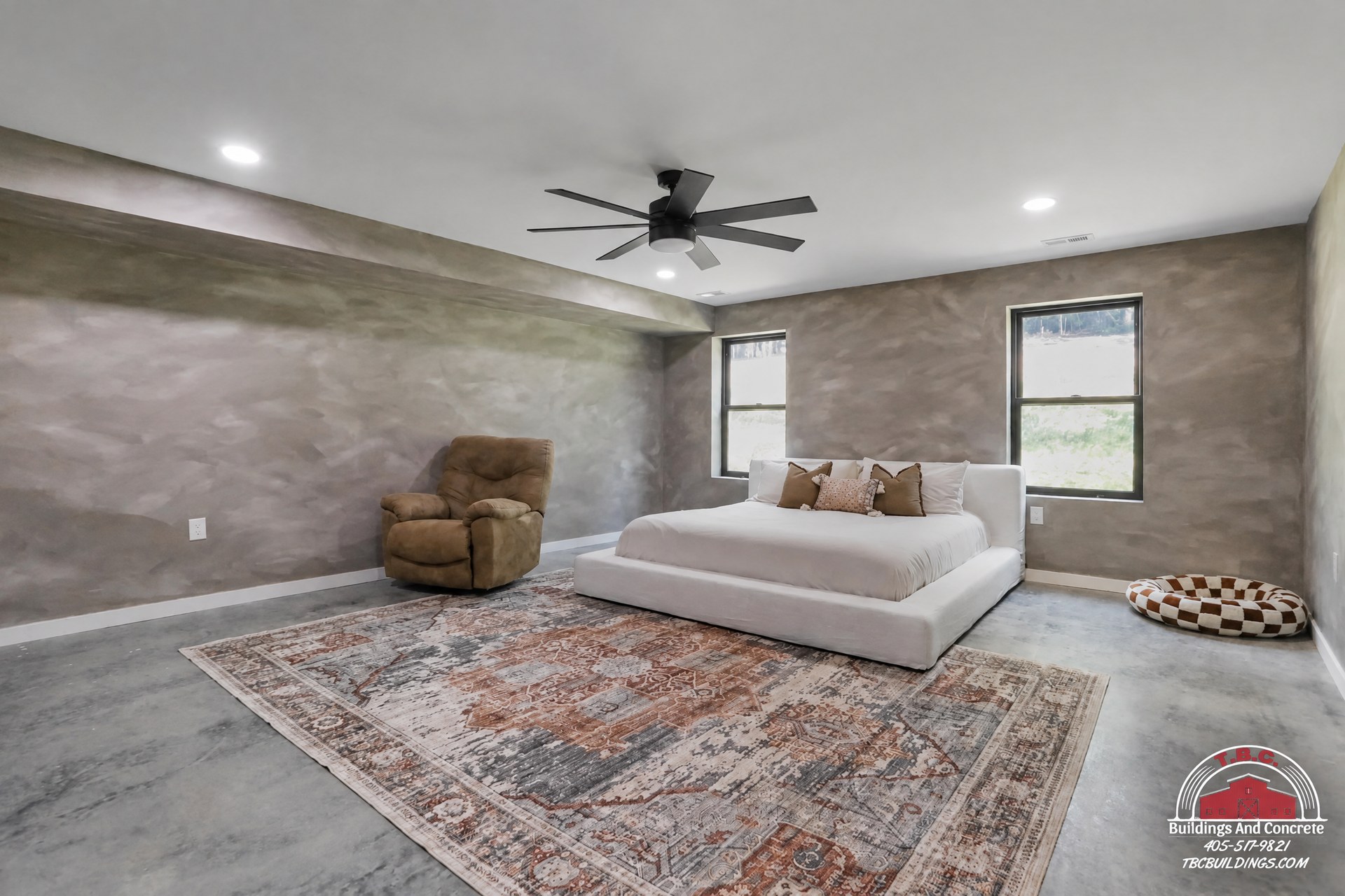 TBC project photo of a finished great room with a sectional sofa, area rug, ceiling fan, and gray walls.