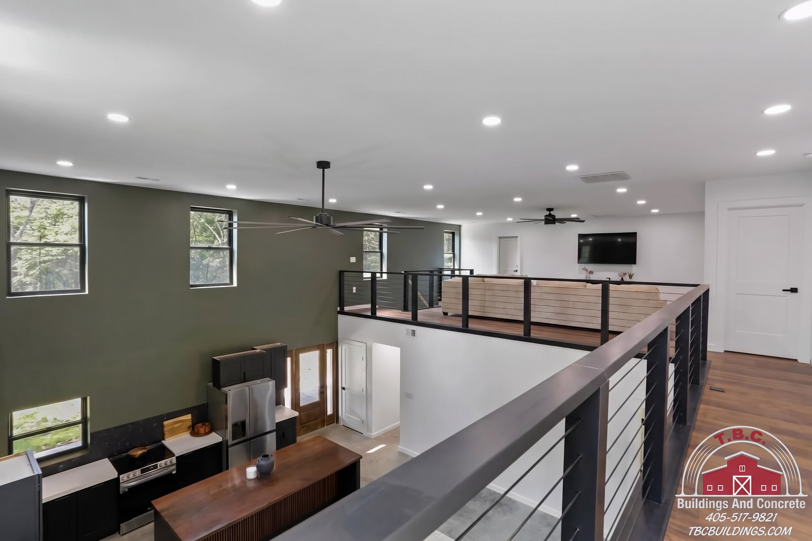 TBC project photo of an upstairs loft with black metal railing overlooking the open living area below.