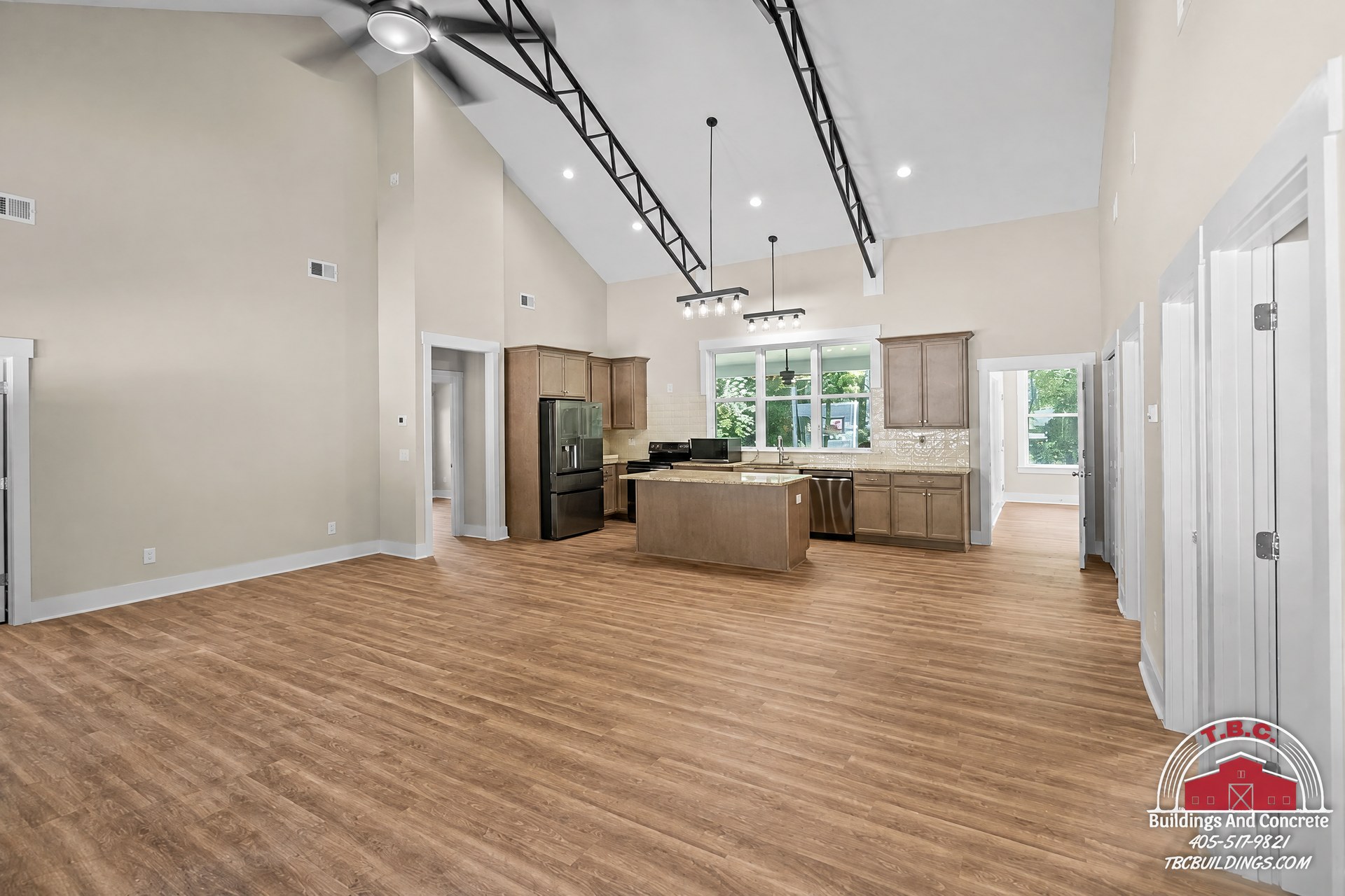 TBC project photo of an open finished room with wood flooring, white walls, a ceiling fan, and windows.