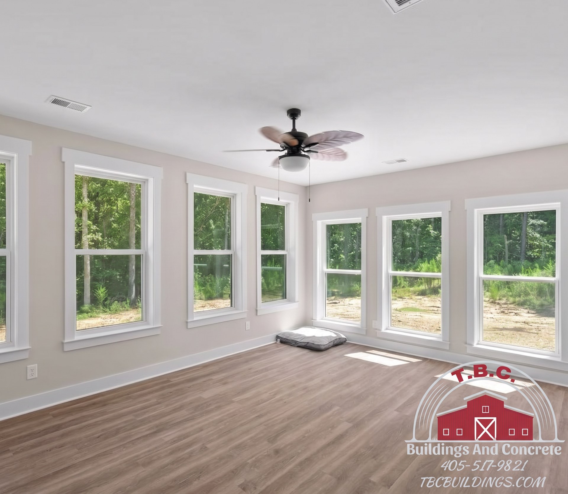 TBC project photo of an empty windowed room with wood flooring, a ceiling fan, and multiple glass doors.