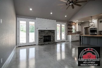 TBC project photo of an open-plan room with polished concrete flooring, a kitchen, ceiling fan, and glass doors.