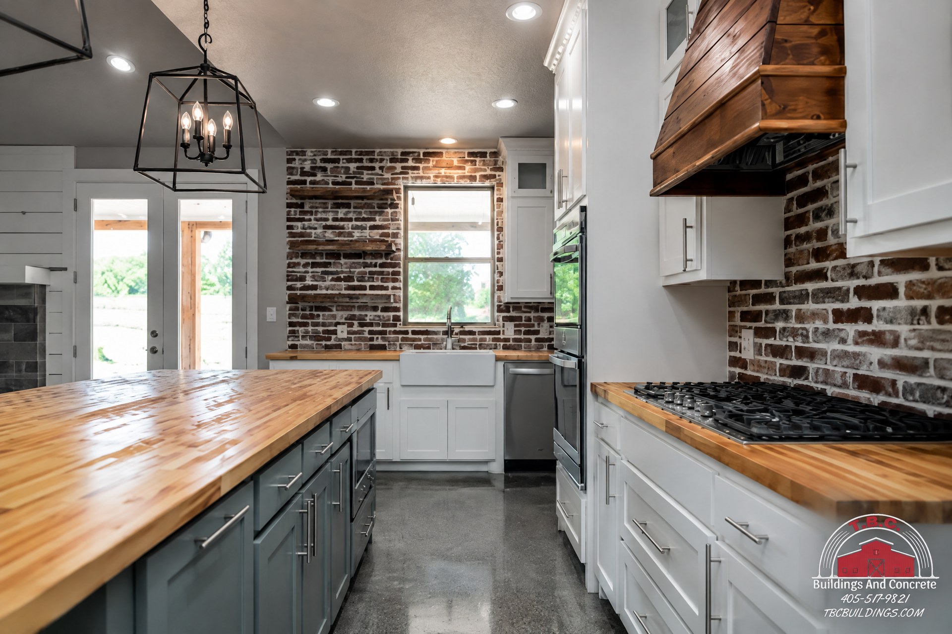 TBC project photo of a kitchen with wood countertops, a dark brick backsplash, white cabinets, and glass doors.