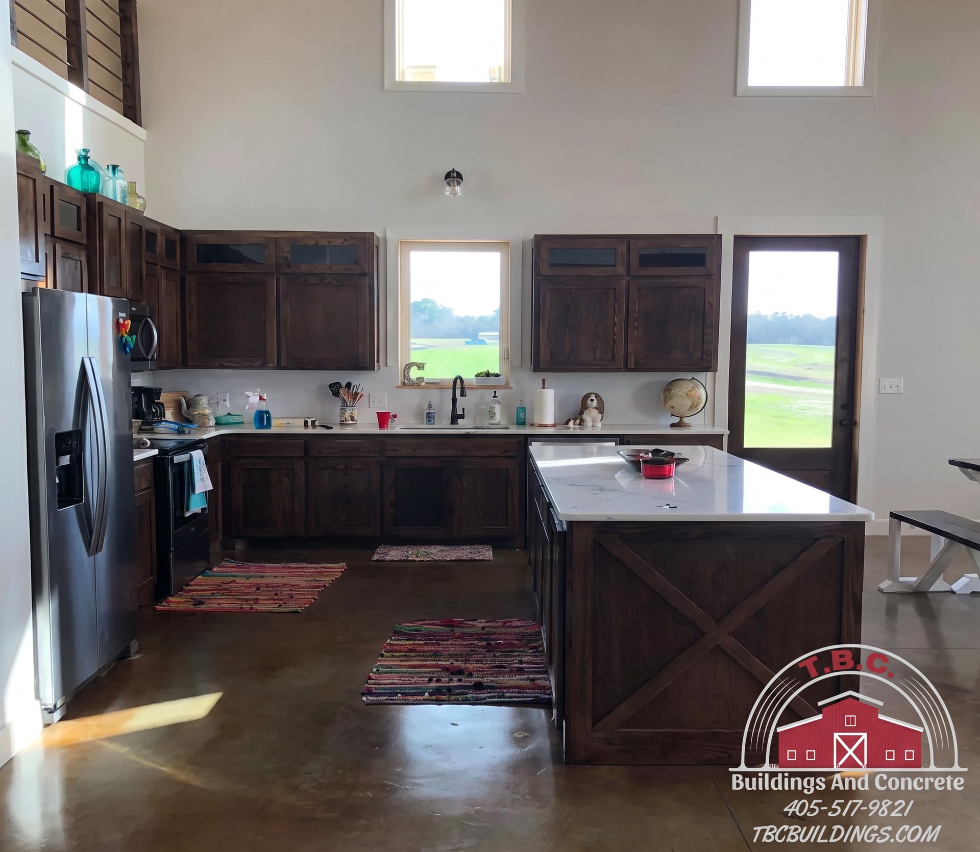 TBC project photo of a kitchen with dark wood cabinetry, a stainless refrigerator, and a window.