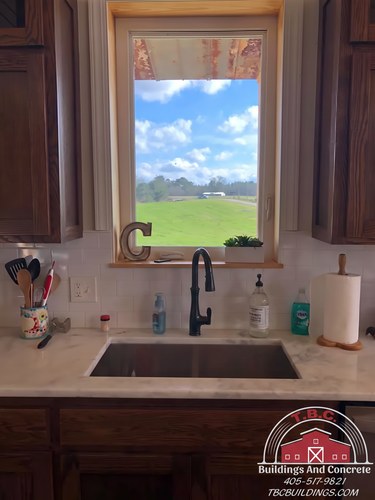 TBC project photo of a kitchen sink beneath a window in dark wood cabinetry.