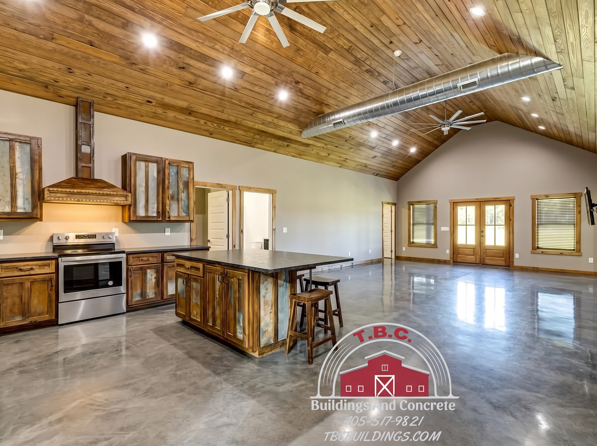 TBC project photo of an open kitchen with wood cabinets, a center island, and a vaulted wood ceiling.